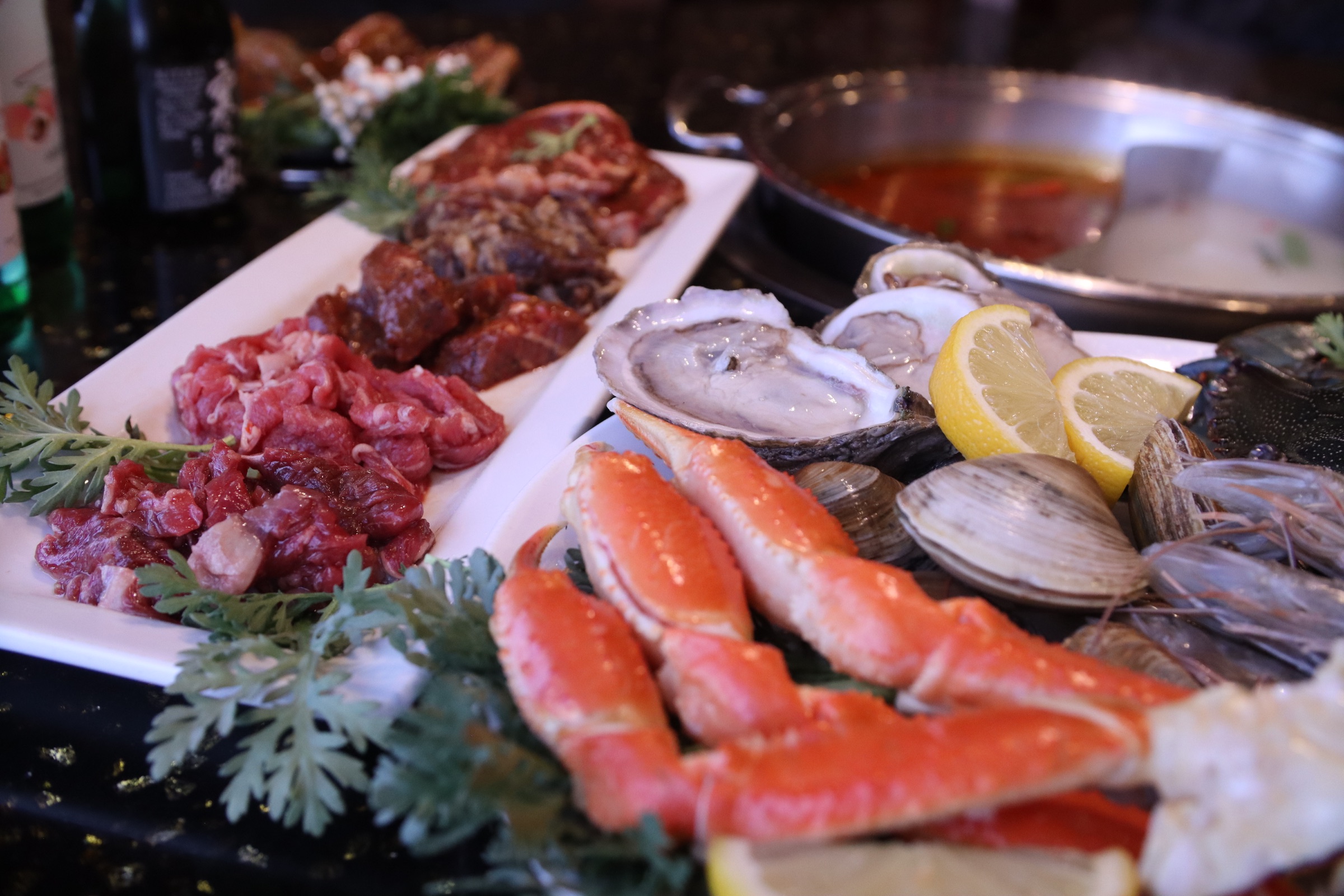 Hotpot, grilled meats, crab, oysters, and seafood prepared for the table